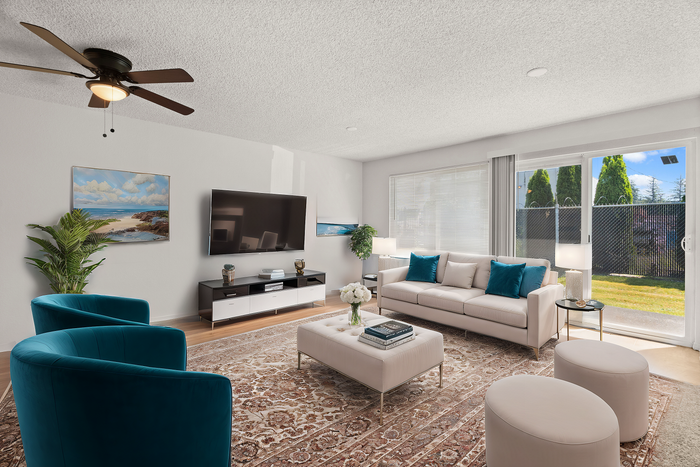 Bright and spacious living room with stylish decor, featuring a large sofa, modern armchairs, and a wall-mounted TV.