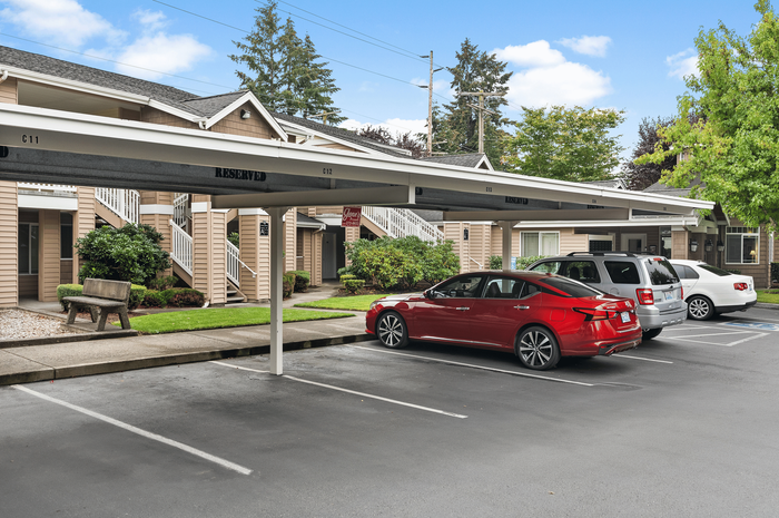 Inviting apartment complex showcasing ample parking, lush greenery, and outdoor seating against a backdrop of charming architecture.