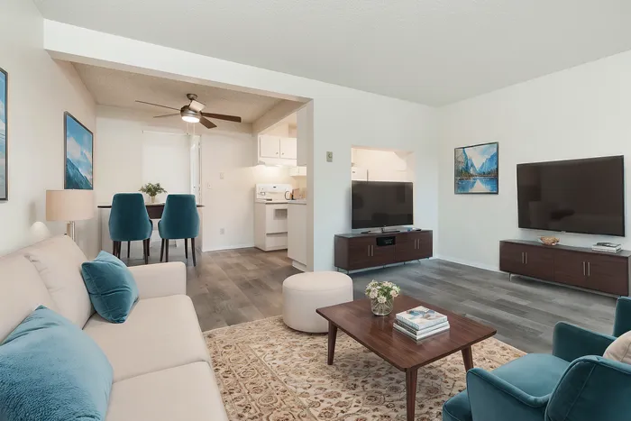 Elegant living room with plush seating, modern entertainment setup, and cozy dining area featuring a chic table with blue chairs.