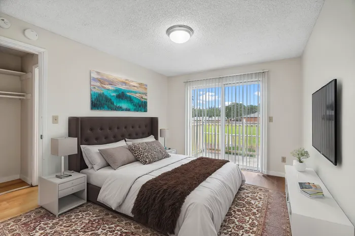 Bright and inviting bedroom with a plush bed, elegant decor, large window with scenic views, and modern wall-mounted TV.