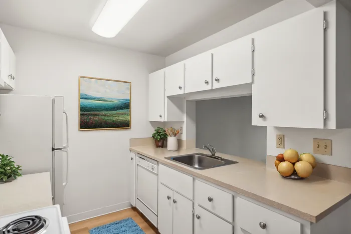 Charming and bright kitchen with sleek white cabinets, stylish countertops, and decorative artwork, perfect for culinary creativity.