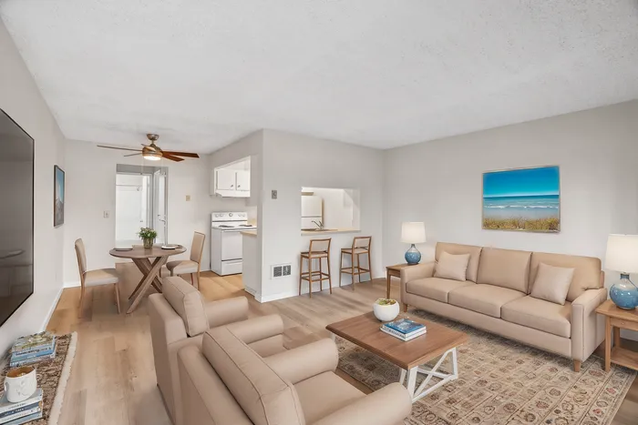 Chic living space with elegant beige furniture, modern dining area, and cozy open kitchen featuring bar seating, perfect for entertaining.