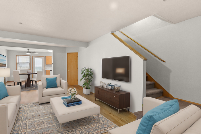 Elegant living room with chic furniture, wooden floors, stylish decor, and a modern TV unit leading to a dining area and kitchen.