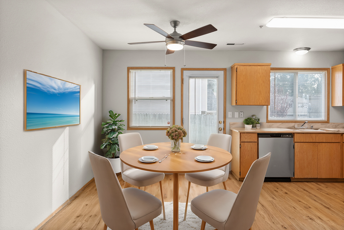 Bright dining area with chic wooden table, elegant white chairs, and modern kitchen setting, accented by a vibrant seaside art piece.