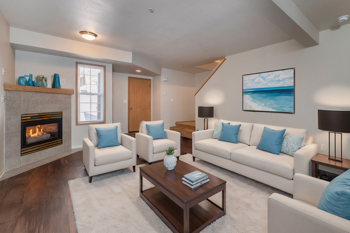 Inviting living room with a cozy fireplace, elegant white sofas, and vibrant blue accents, perfect for relaxation and entertaining.