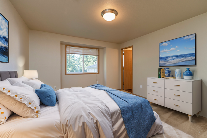 Serene bedroom with plush bedding, elegant dresser, and tranquil window view, perfect for relaxation.