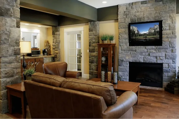Charming living room with rustic stone fireplace, leather seating, and elegant decor, creating a cozy and inviting atmosphere.