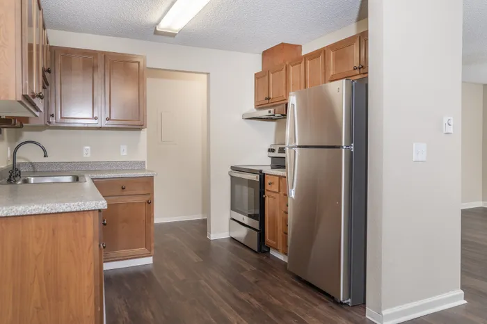 Modern kitchen with wood cabinetry, stainless steel appliances, and a sleek electric range, complemented by light wood flooring and neutral walls.