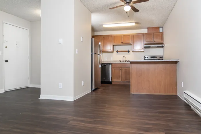 Elegant apartment interior featuring modern wooden cabinets and stainless steel appliances in a stylish open-plan kitchen with warm wood flooring.