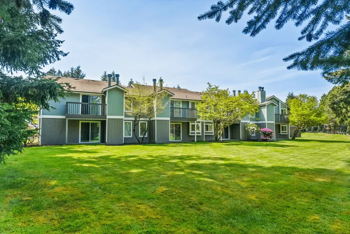Charming apartment complex exterior with lush greenery and blooming flowers.