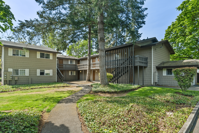Picturesque view of a two-story apartment building surrounded by lush greenery.