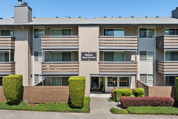 Charming exterior of the Maples Apartments featuring wooden balconies and lush greenery.