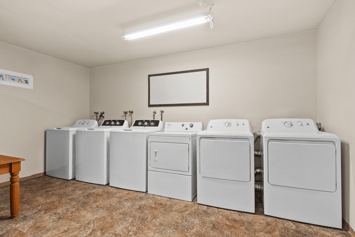 Spacious laundry room featuring multiple sleek washing and drying machines, ideal for efficient living.