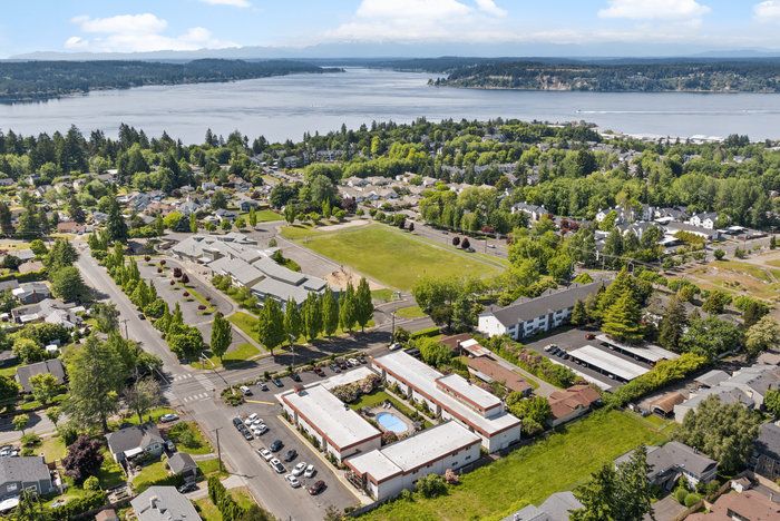 Breathtaking aerial view of a vibrant neighborhood with lush greenery, modern apartments, and a beautiful waterfront backdrop.