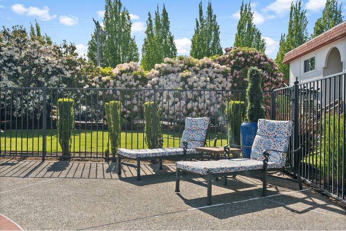 Charming outdoor space with cozy floral lounge chairs and lush garden views, perfect for relaxation and enjoying sunny days.