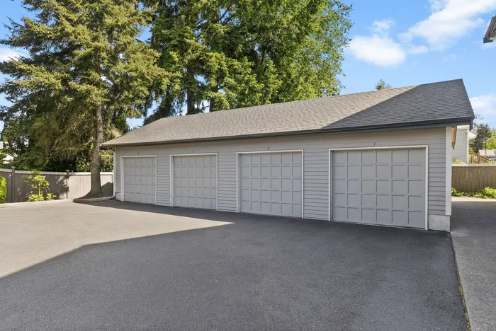 Spacious multi-car garage set amidst lush greenery, offering ample parking and storage solutions.