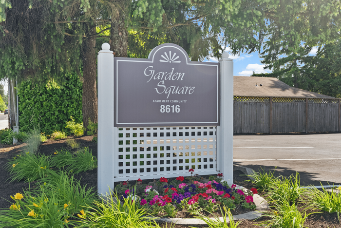Inviting entrance sign for Garden Square apartment community surrounded by lush greenery and vibrant flowers.