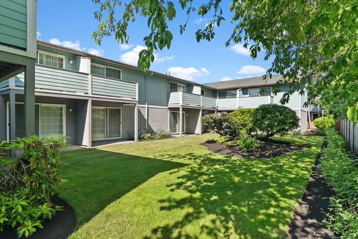 Bright and inviting exterior of modern apartments with lush green lawns and private balconies creating a serene living environment.