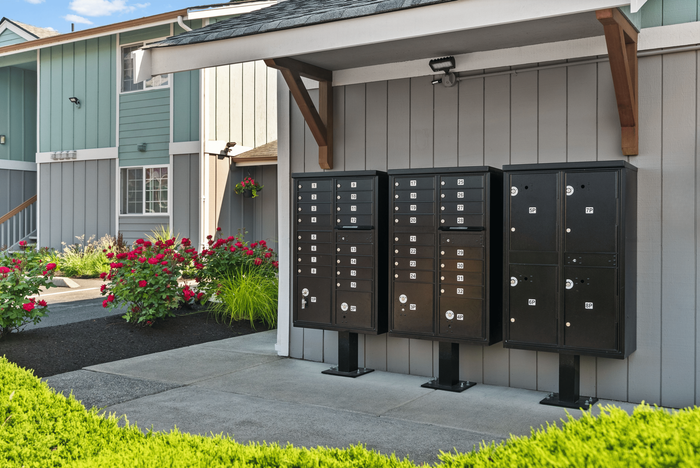 Charming apartment exterior with manicured landscaping, featuring vibrant flower beds and sleek black mailboxes.