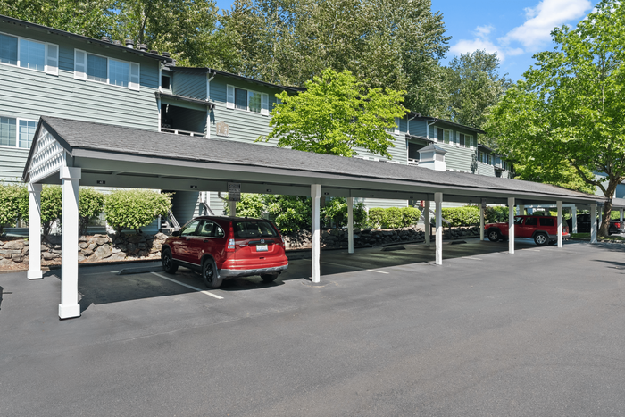 Apartment complex with ample shaded parking and lush greenery.