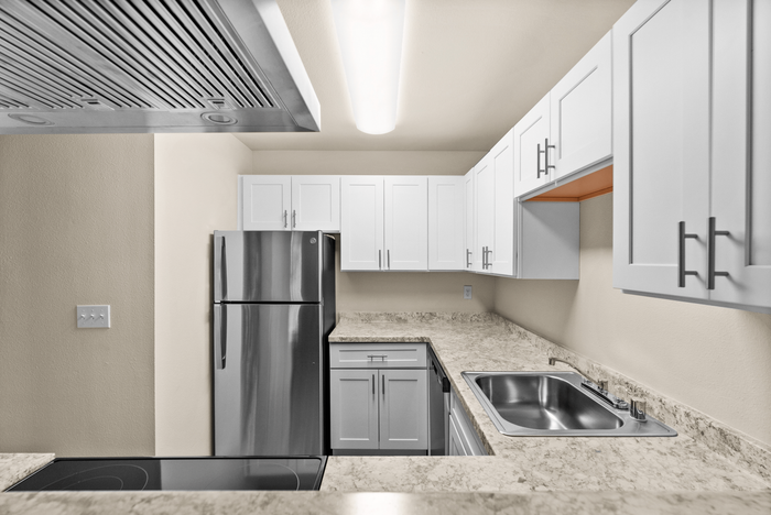 Modern kitchen with sleek stainless steel appliances, elegant white cabinetry, and polished stone countertops, offering ample space and contemporary style.