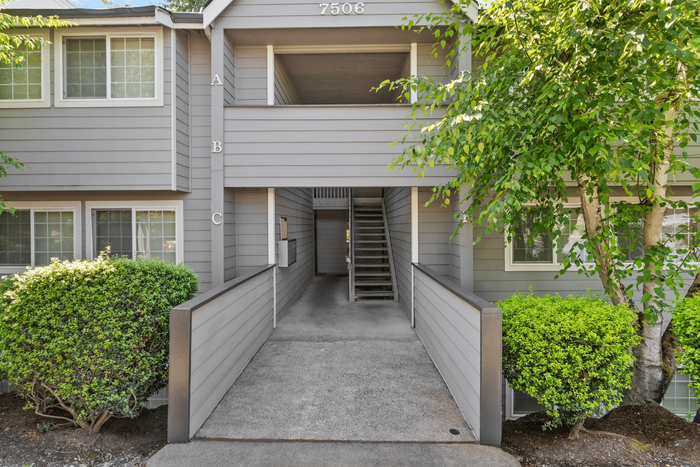 Charming apartment entrance surrounded by lush greenery and contemporary architecture.