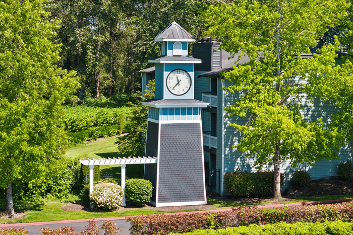 Charming blue tower with a clock, nestled among lush trees and vibrant greenery, offering timeless elegance and serene views.