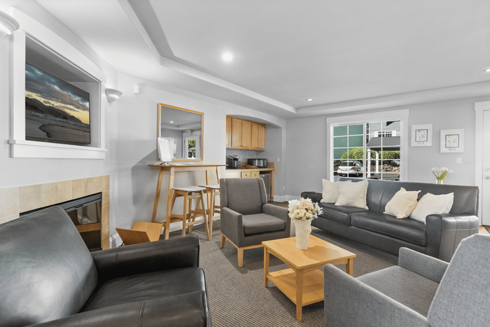 Inviting modern living room with sleek leather sofas, a cozy fireplace, and a stylish breakfast bar. Bright interiors with large windows and contemporary decor.