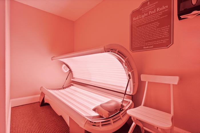 Luxurious wellness room featuring a modern red light therapy pod and comfortable seating, perfect for relaxation and rejuvenation.