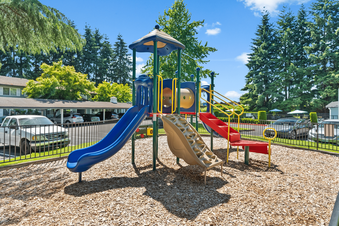 Charming playground featuring colorful slides and climbing structures in a vibrant community setting.