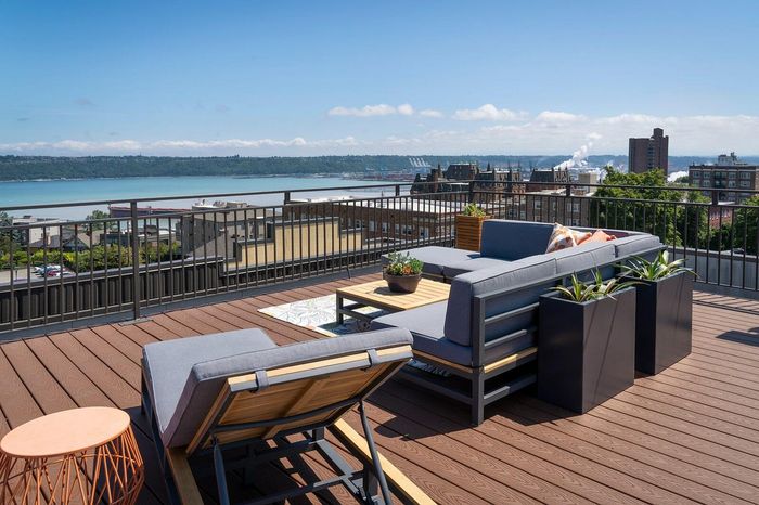 Chic rooftop terrace with modern seating, lush planters, and stunning waterfront views perfect for relaxation.