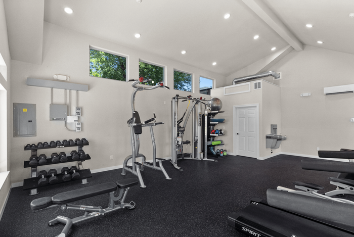 Bright and modern fitness room equipped with weights, exercise machines, and ample space for workouts.