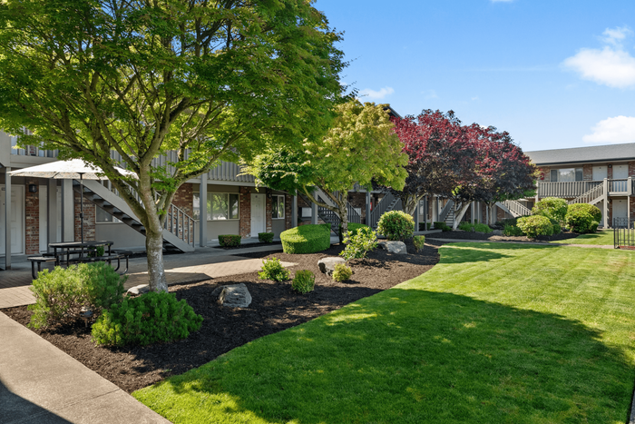 Charming apartment complex with lush green landscaping, vibrant trees, and a tranquil atmosphere.