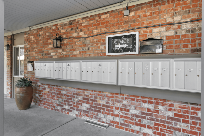 Charming brick-walled mail area with modern mailboxes and rustic decor accents for a welcoming apartment community.