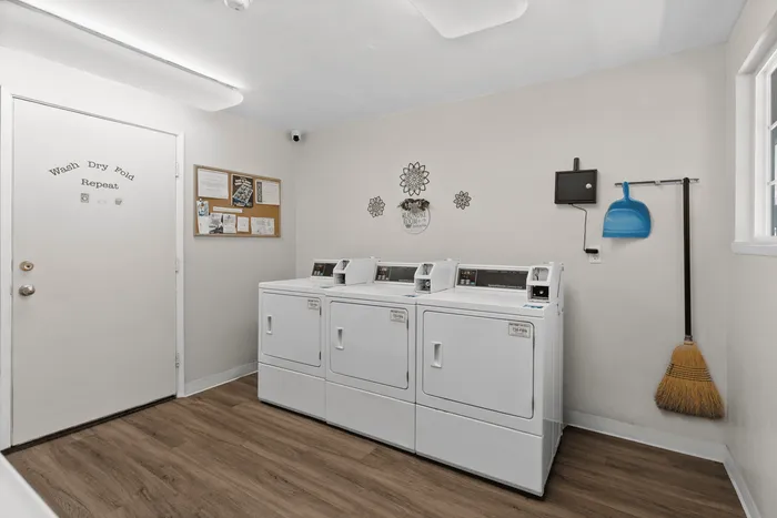 Bright and inviting laundry room with modern washing machines, cozy decor, and convenient bulletin board, ideal for community use.