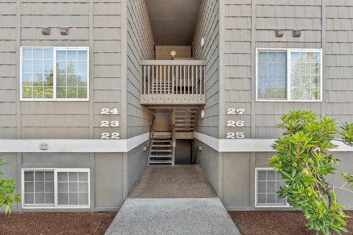 Inviting apartment entrance featuring modern exterior with numbered units and lush green landscaping.