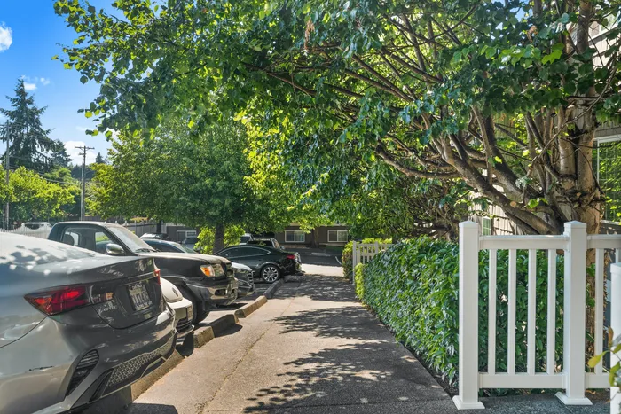 Charming apartment entrance with lush greenery, shaded pathway, and convenient parking, creating an inviting and tranquil atmosphere.