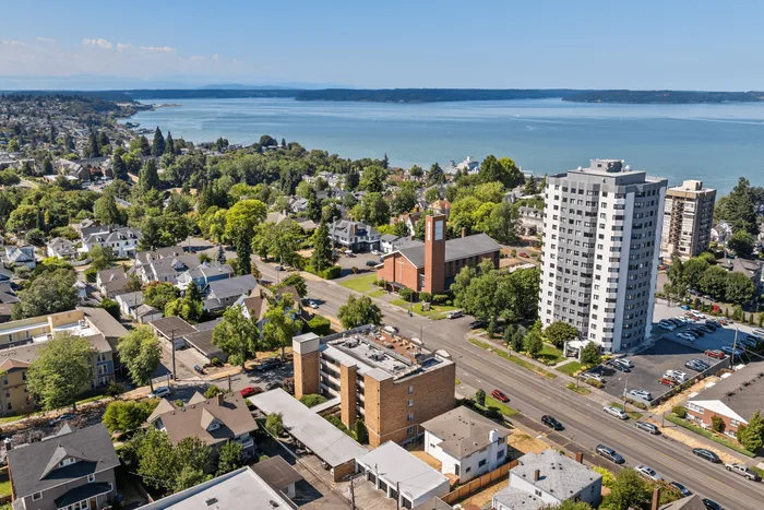Aerial view of a vibrant coastal neighborhood featuring modern apartments, lush greenery, and a stunning ocean backdrop, perfect for serene living.