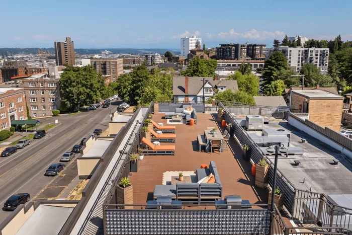 Stunning rooftop view featuring a chic outdoor lounge area with stylish seating, lush greenery, and panoramic cityscape vistas.