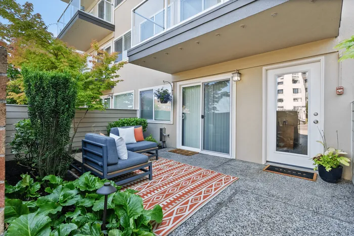 Charming patio space with cozy outdoor seating and vibrant decor, surrounded by lush greenery and modern apartment architecture.