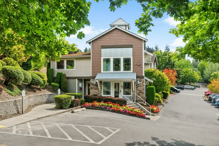 Charming apartment complex surrounded by lush greenery with vibrant flower beds and ample parking.