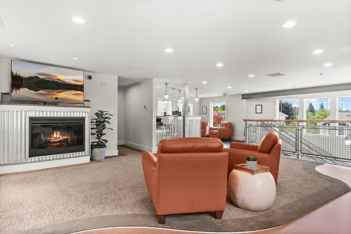 Inviting open-concept living area with modern fireplace, plush orange seating, and bright natural light, ideal for relaxation and gatherings.