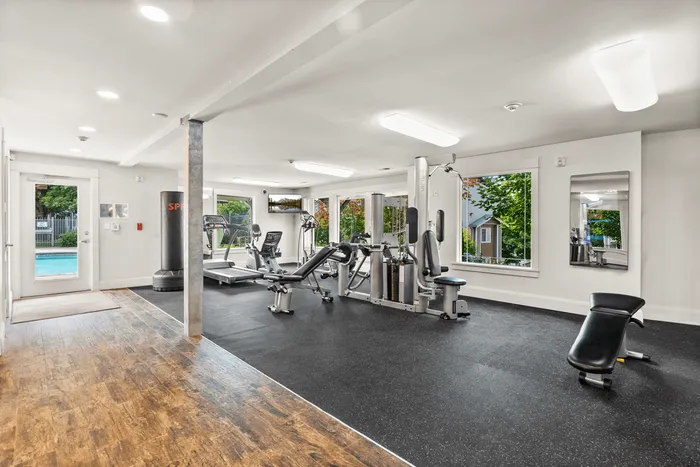 Bright and modern fitness center with state-of-the-art equipment and large windows overlooking a serene pool area.