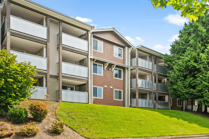 Charming apartment building with spacious balconies and lush green surroundings, perfect for serene living.