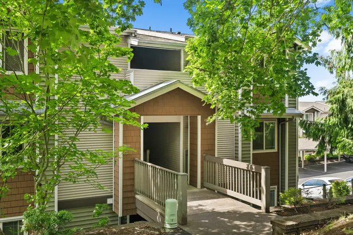 Charming apartment entrance surrounded by lush greenery, offering a serene and inviting atmosphere.