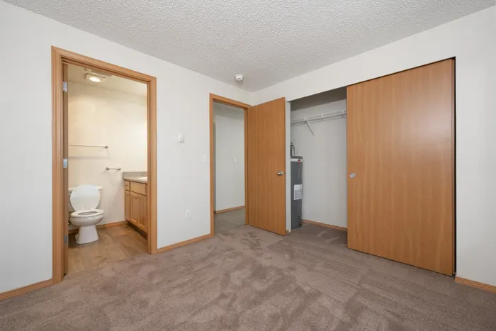 Cozy bedroom with plush carpeting, featuring an en-suite bathroom and ample closet space for convenient living.