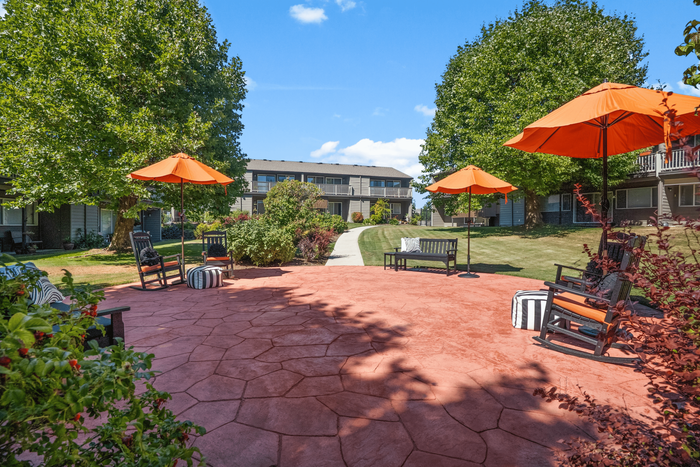 Charming outdoor patio with vibrant orange umbrellas, comfortable seating, and lush greenery, perfect for relaxation and gatherings.