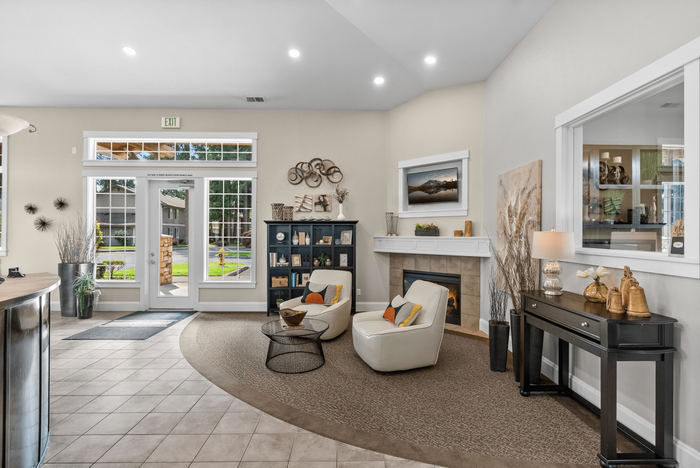 Inviting lobby lounge with modern decor, plush seating by a cozy fireplace, and abundant natural light through large windows.