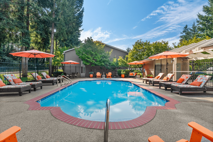 Inviting outdoor swimming pool area with vibrant lounge chairs, umbrellas, and lush greenery, perfect for relaxation.