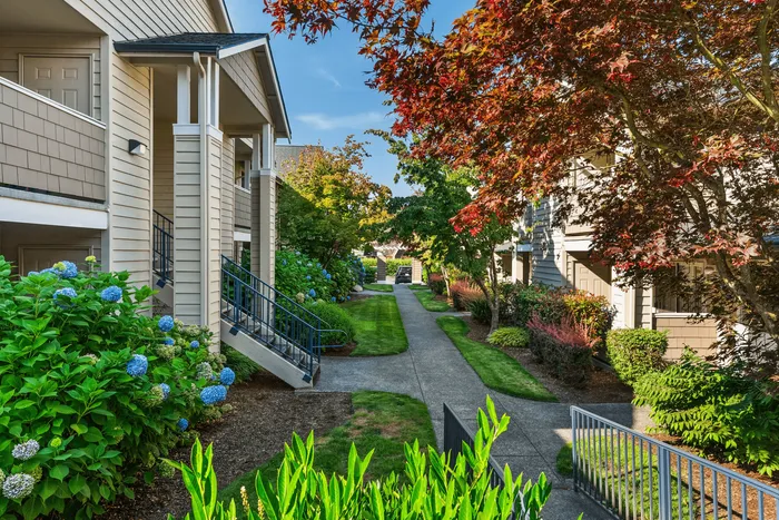 Charming apartment exterior showcasing lush landscaping and vibrant greenery, featuring inviting pathways and a tranquil atmosphere.